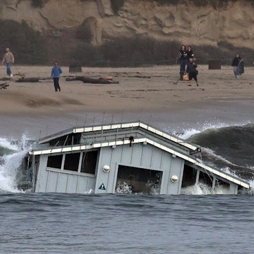 Ein eingestürztes Gebäude einer Werft schwimmt im Meer.
