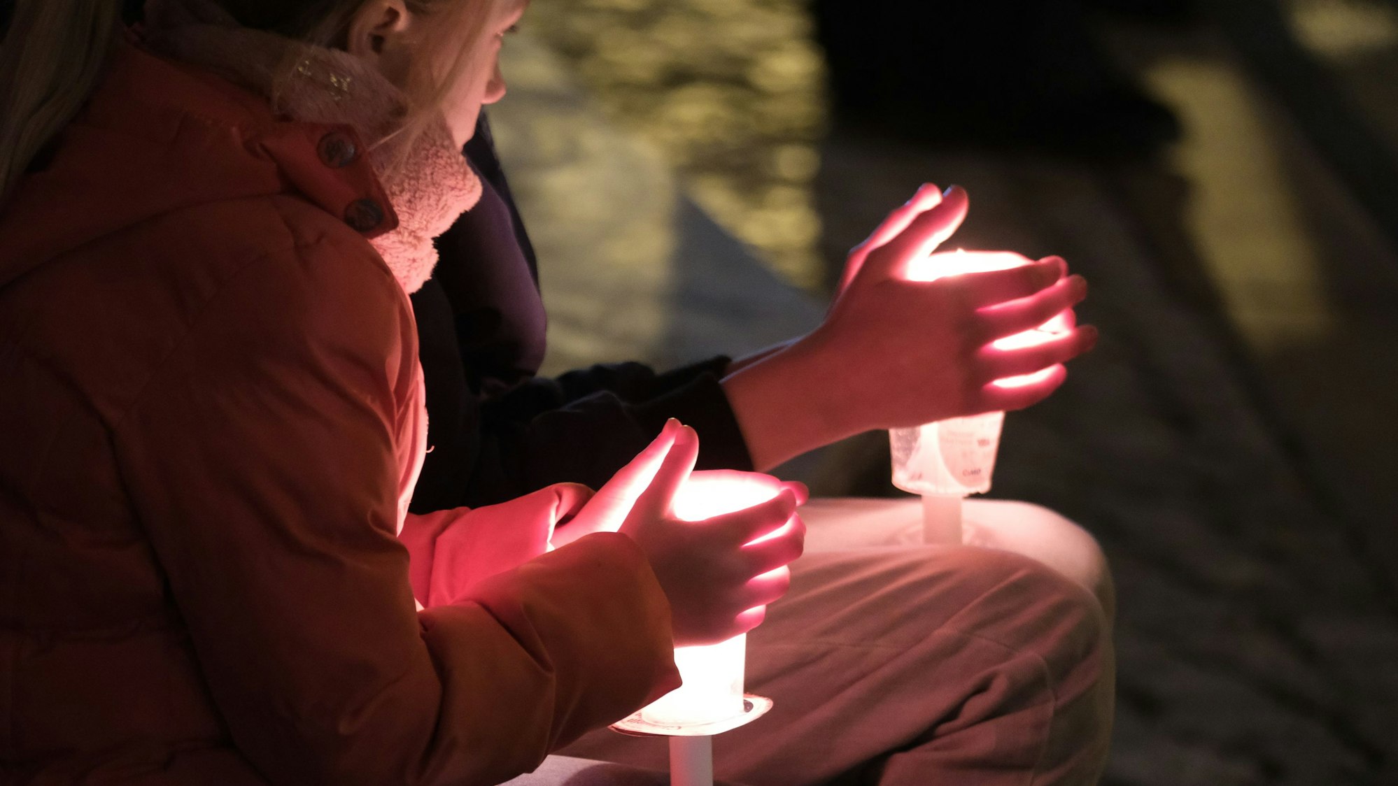 Menschen sitzen mit Kerzen in der Hand auf der Straße in Magdeburg.