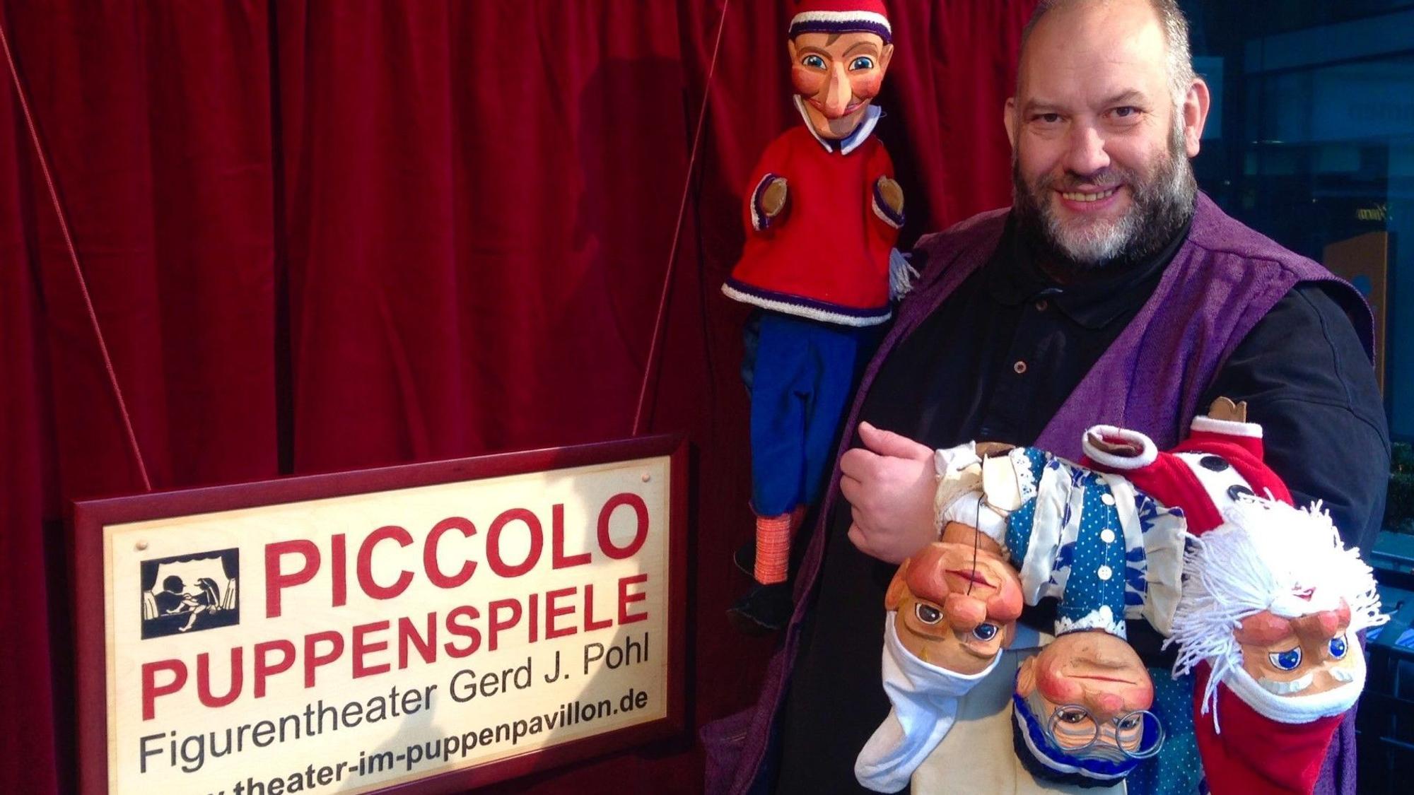 Puppenspieler Gerd J. Pohl steht mit Handpuppen im Bensberger Puppenpavillon.