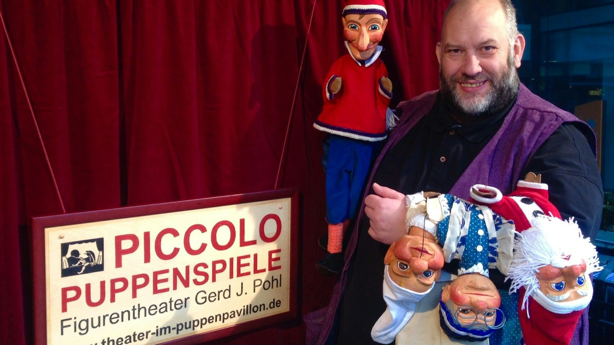 Puppenspieler Gerd J. Pohl steht mit Handpuppen im Bensberger Puppenpavillon.
