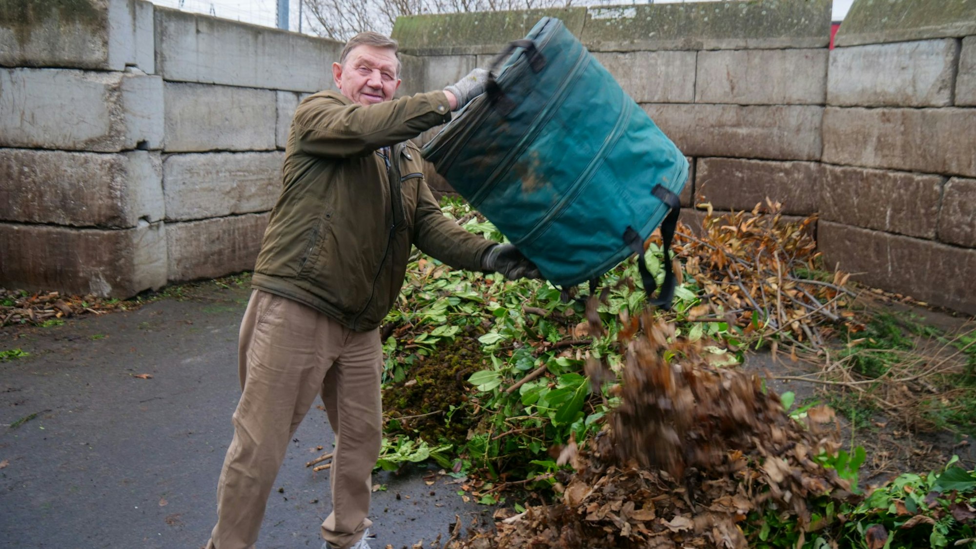 Ein Mann leert einen Sack mit Grünabfällen aus.