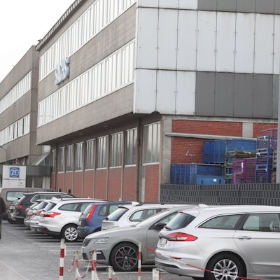 Menschen gehen an einem Industriegebäude vorbei.