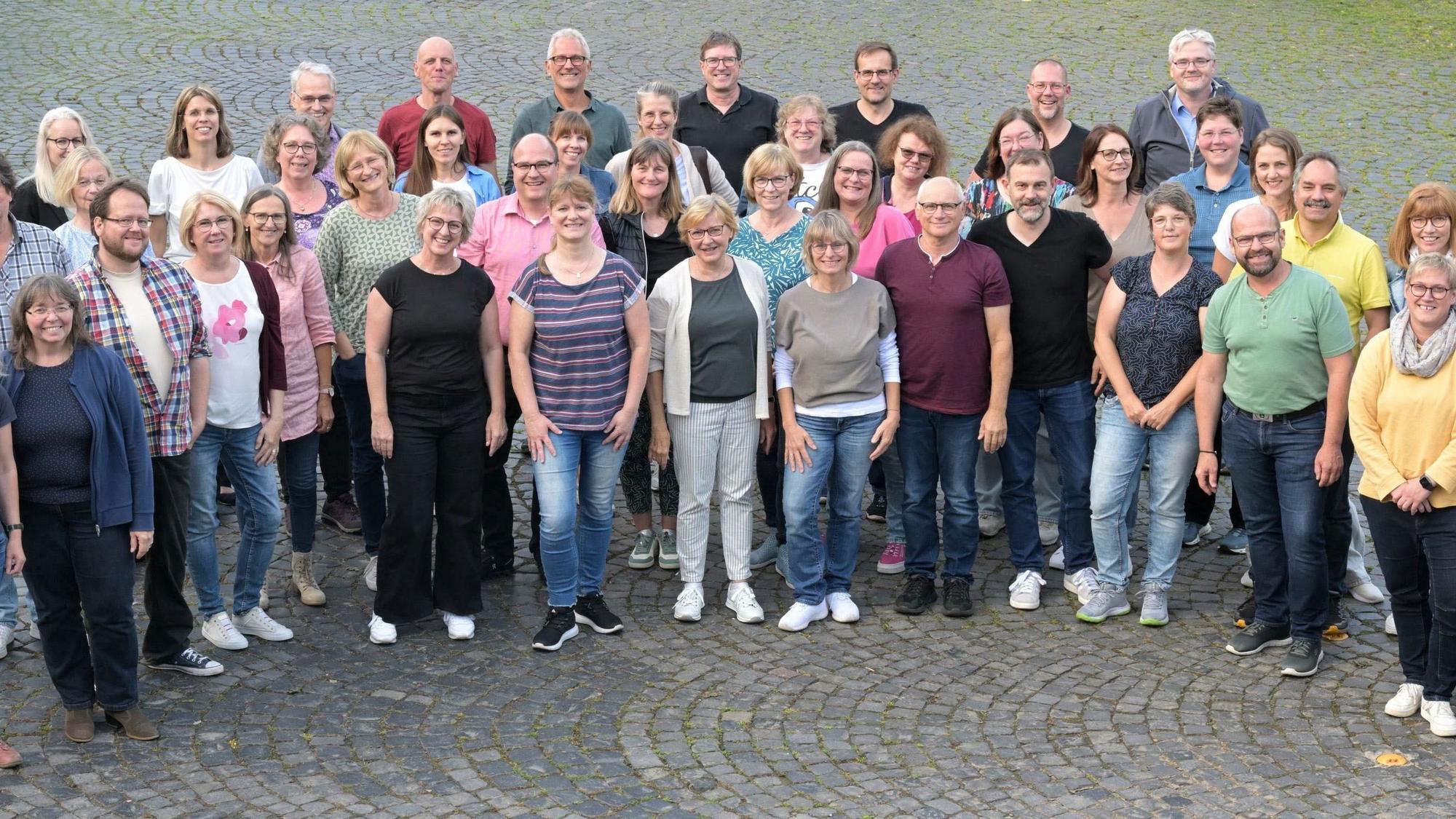 Der A-Cappella-Chor Kürten steht auf einem Platz mit Kopfsteinpflaster.
