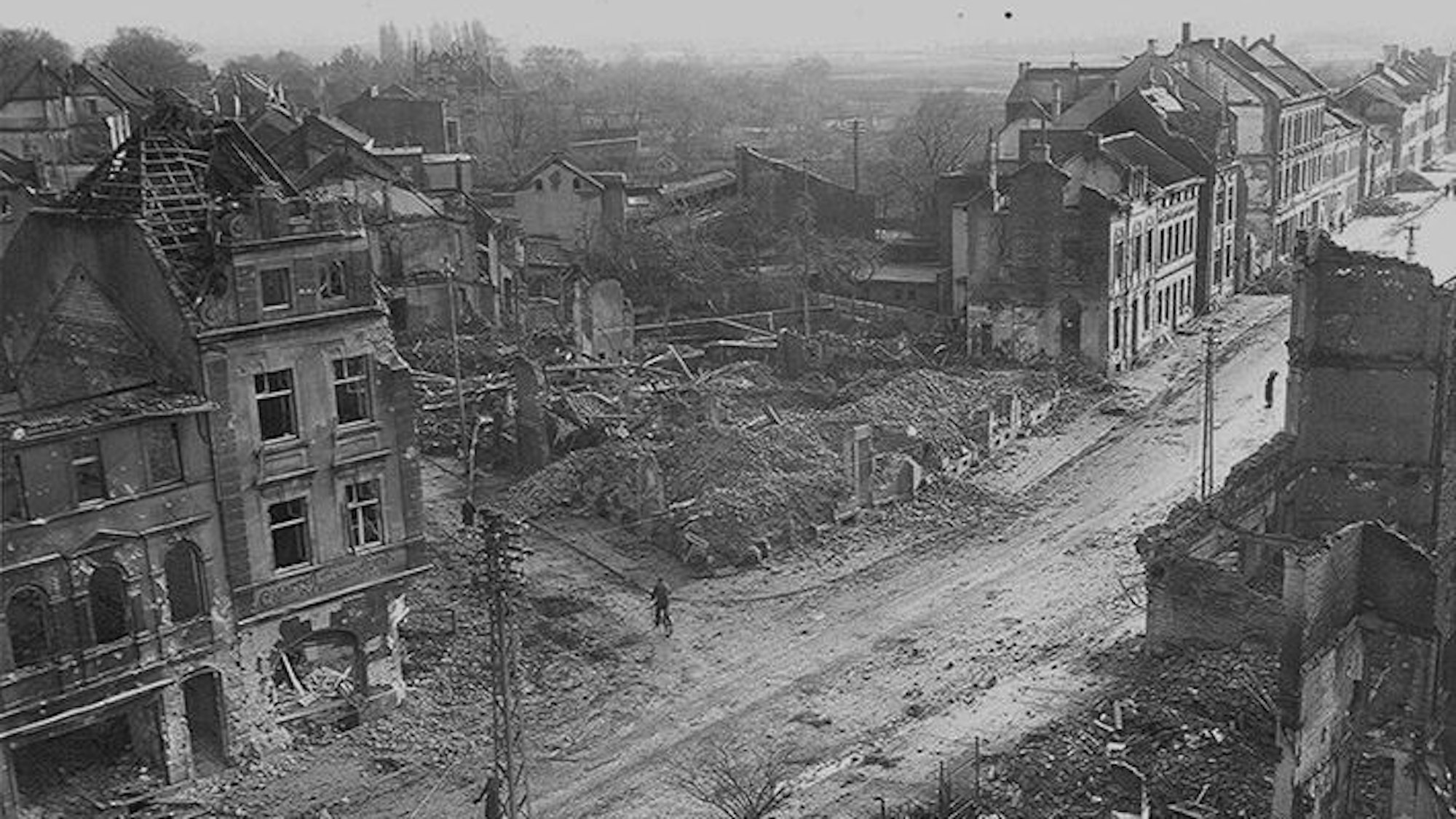 Zu sehen ist eine Schwarz-weiß-Aufnahme, die nach dem Bombenangriff 1944 entstanden ist und zerstörte Häuser zeigt.