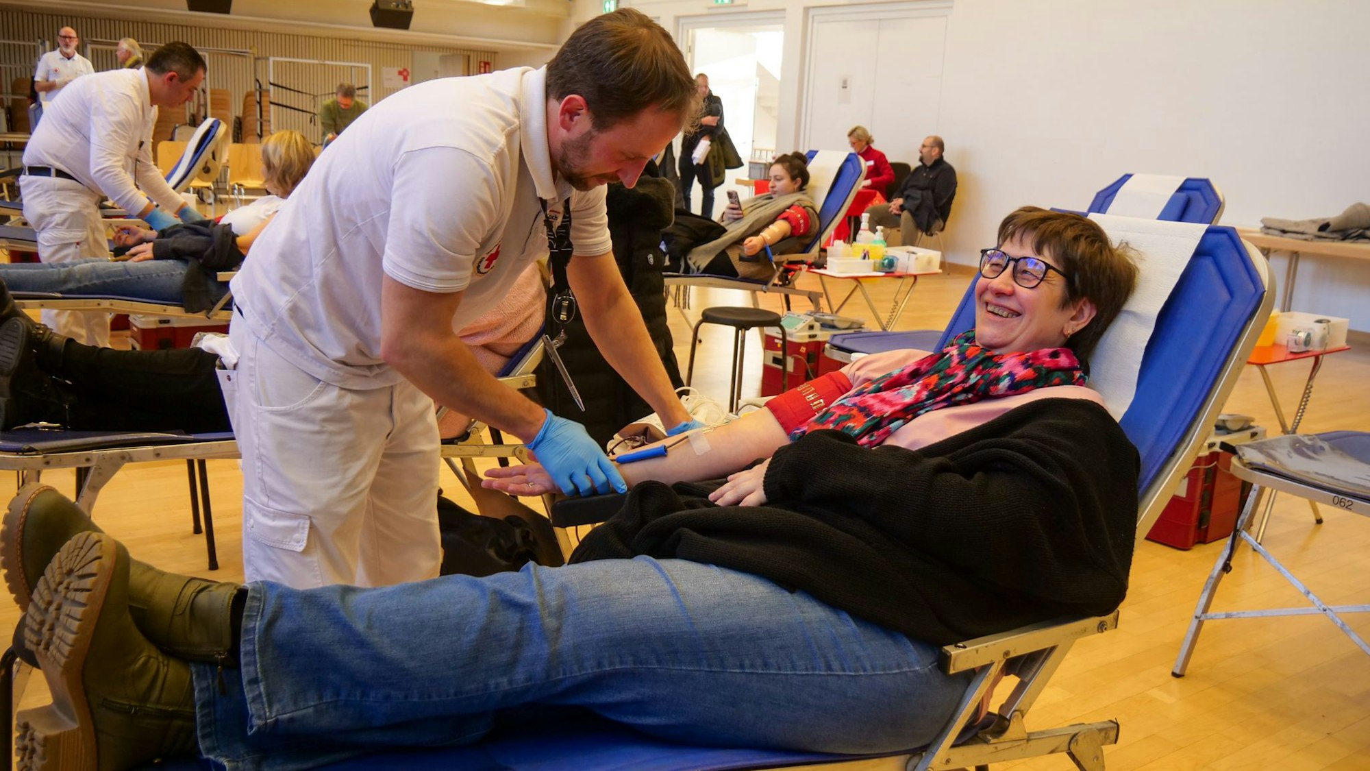 Ein Mann nimmt einer Frau Blut ab.