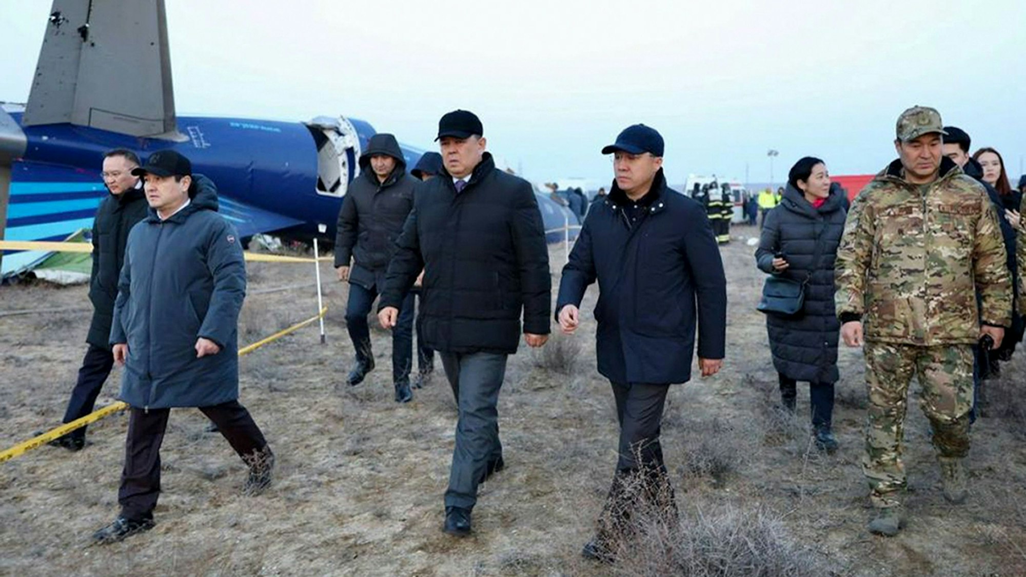 Mitglieder einer Untersuchungskommission und örtliche Beamte gehen am Wrack der Embraer 190 von Azerbaijan Airlines vorbei.