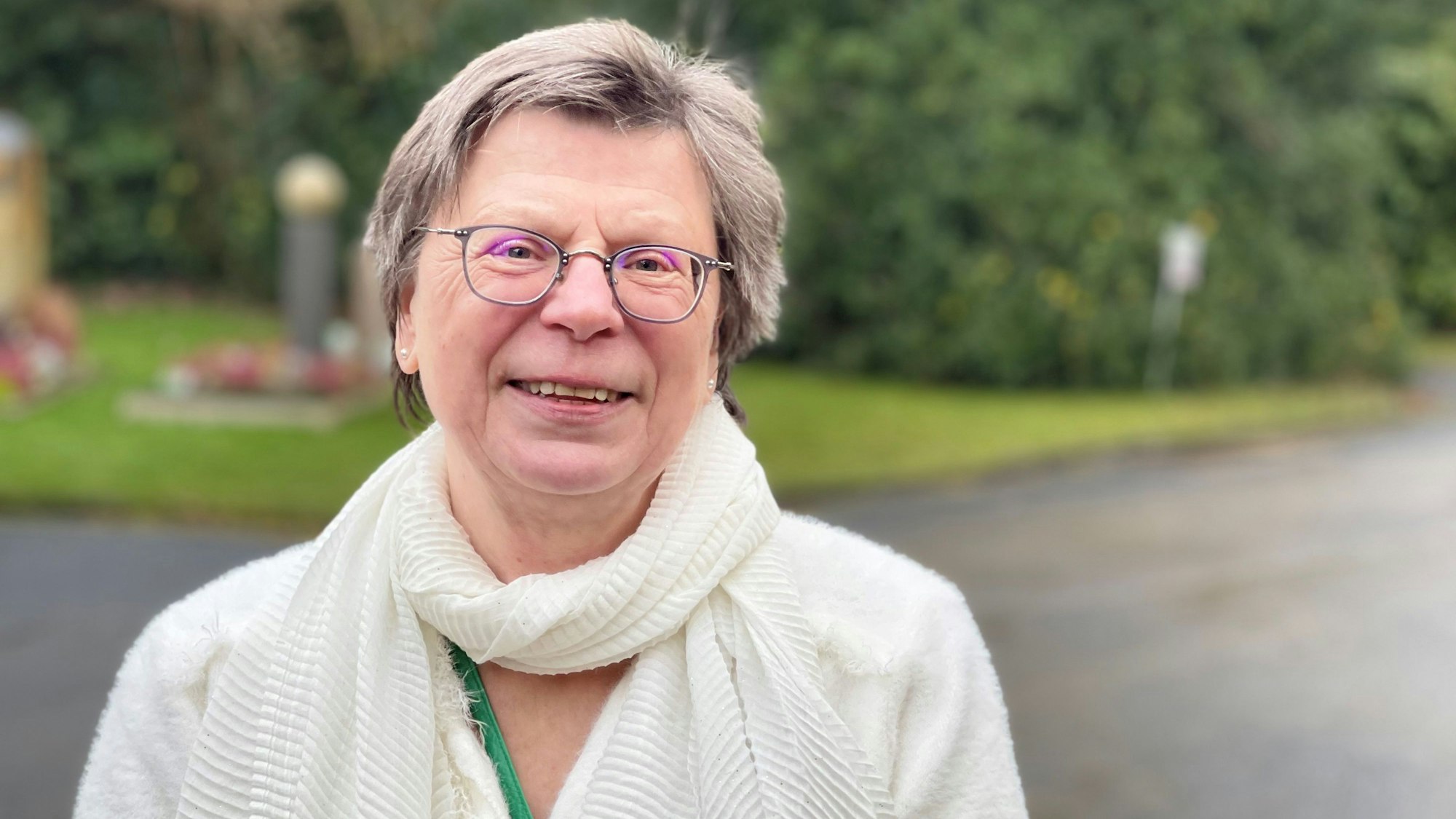 Eine Frau steht im Eingangsbereich eines Friedhofs.