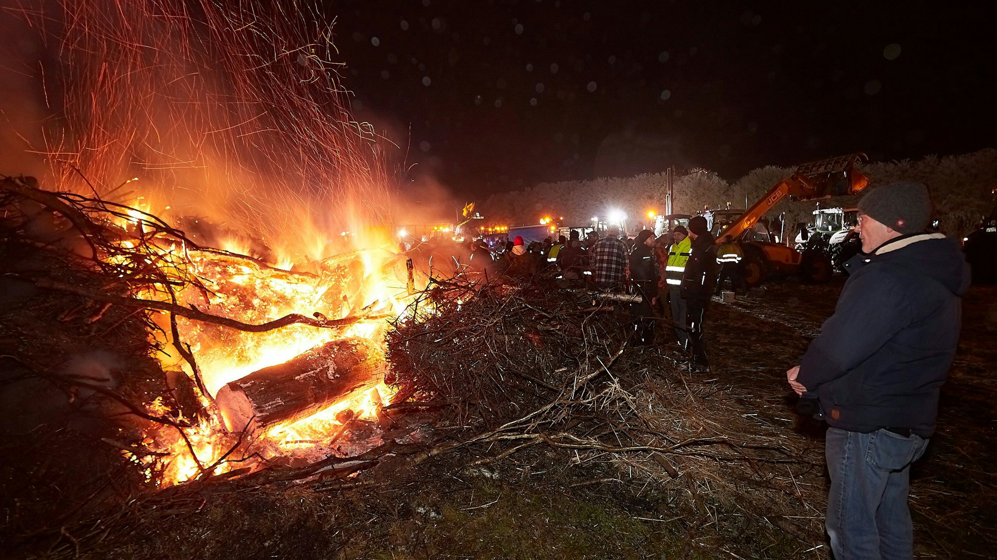 Zahlreiche Menschen haben sich in der Dunkelheit um ein Mahnfeuer versammelt.
