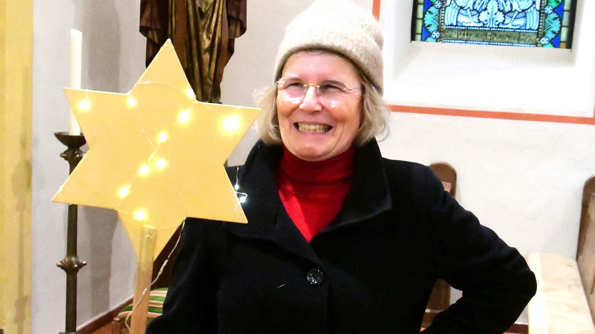 Antje Gräfin von Plettenberg steht in einer Kirche und hält einen mit LED-Lämpchen dekorierten Stern.