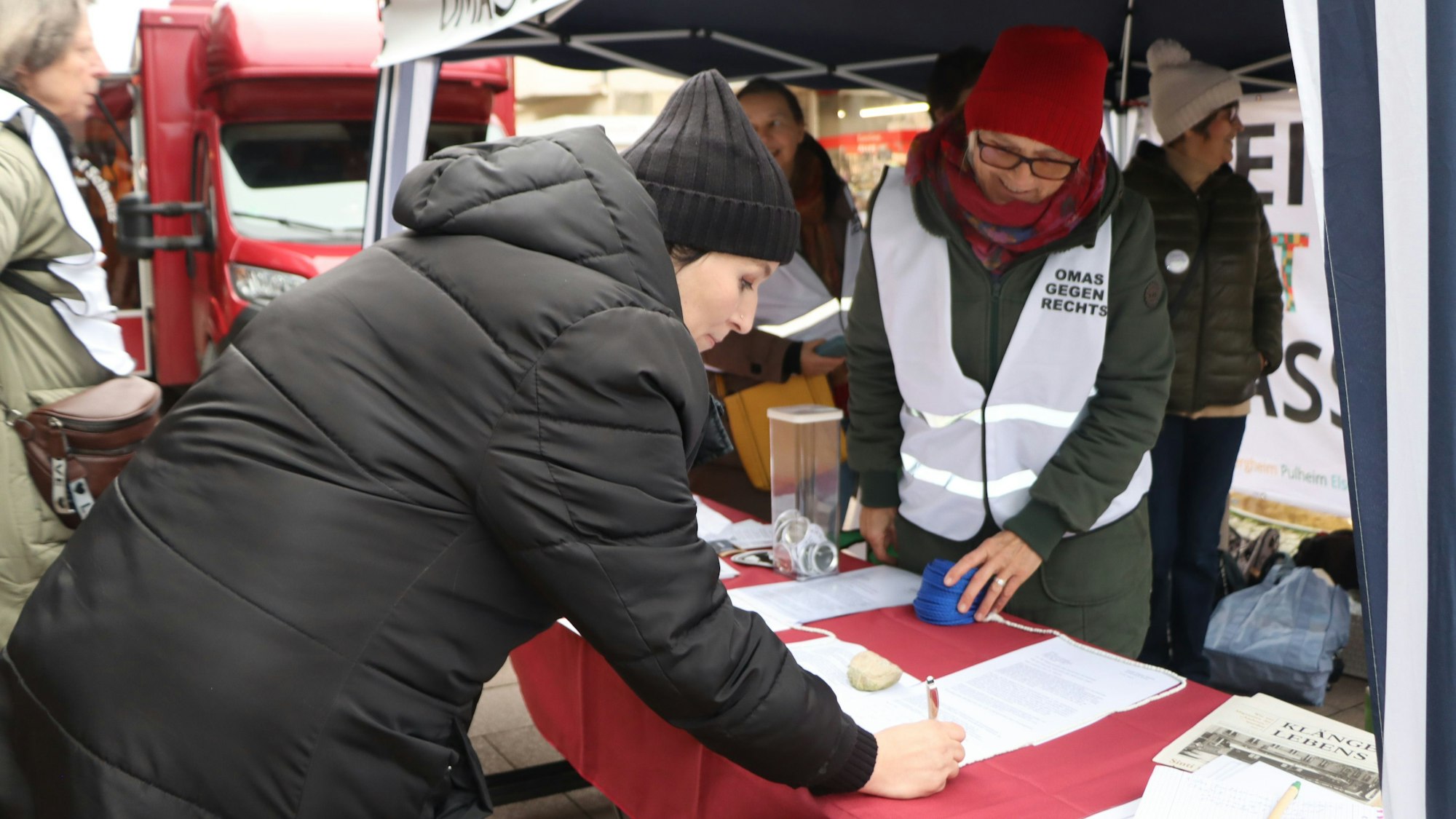 Das Foto zeigt, wie eine junge Frau am Infostand der „Omas gegen Rechts“ Brühl einen Zettel unterschreibt.