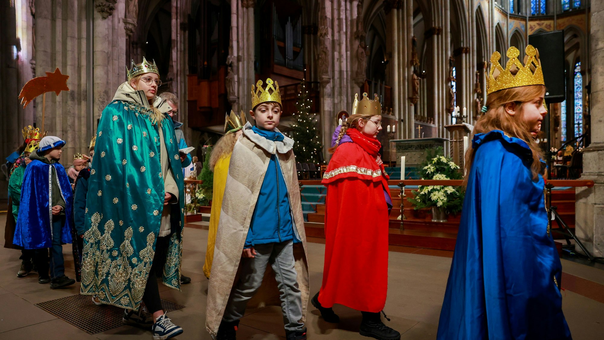 Kinder verkleidet als Heilige Drei Könige gehen durch den Kölner Dom.