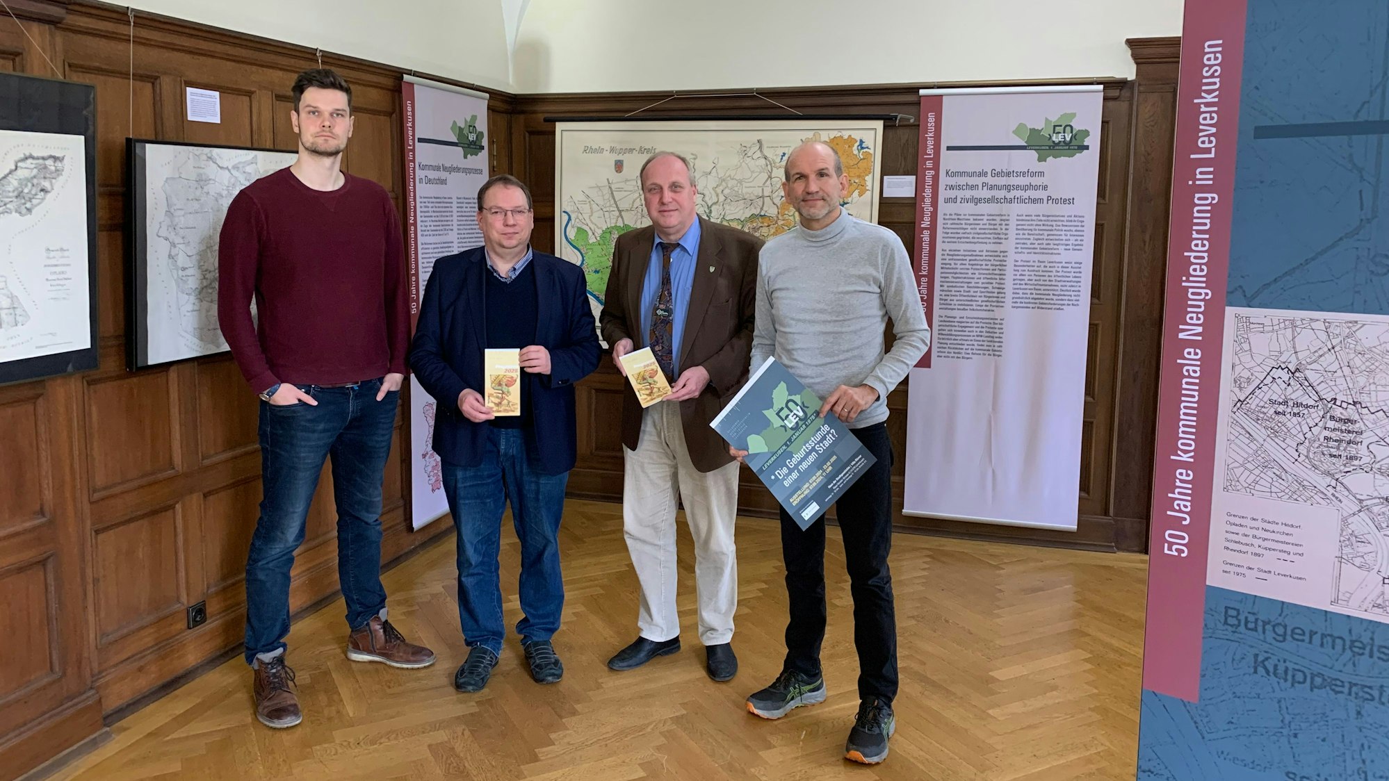 Vier Männer stehen nebeneinander in einem Ausstellungsraum.