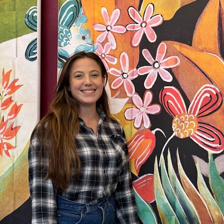 Eine Frau steht vor einer bunten Wand.