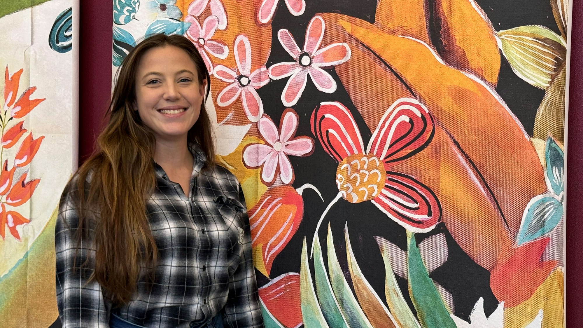 Eine Frau steht vor einer bunten Wand.