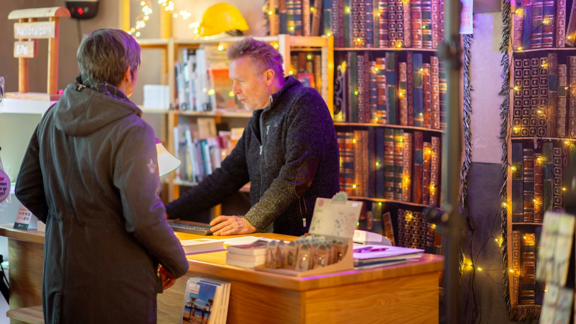 Ein Buchverkäufer bedient eine Kundin in seinem Geschäft.