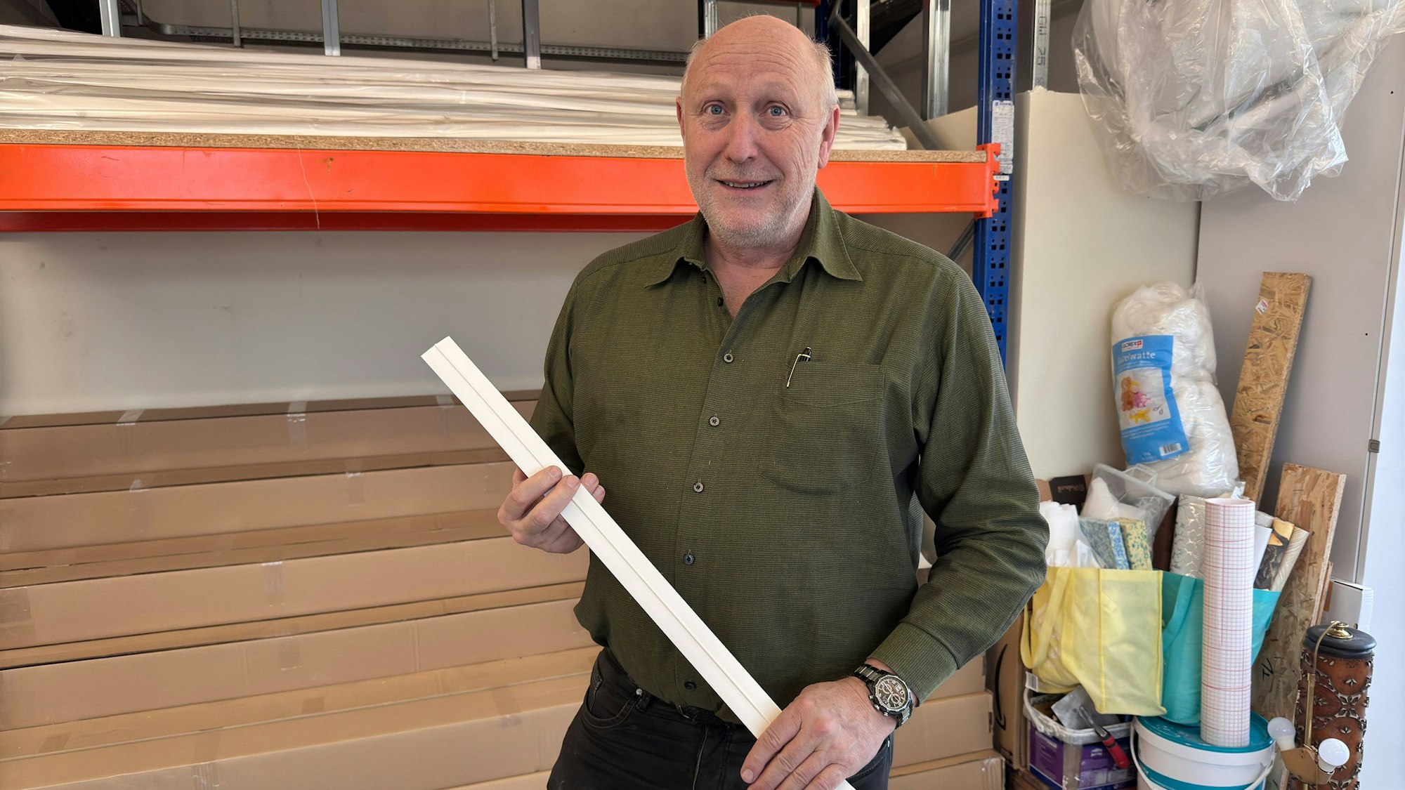 Ein Mann hält eine Schiene für Malerarbeiten in den Händen.