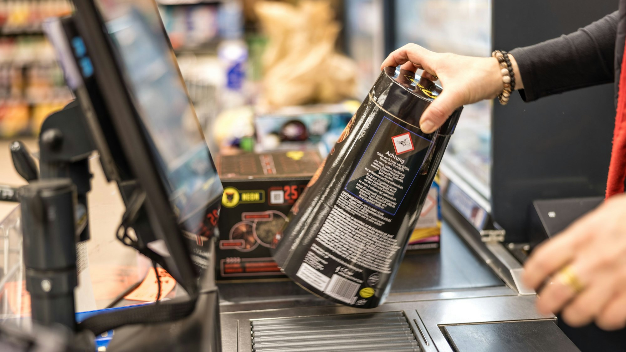 An der Kasse eines Supermarktes wird Feuerwerk über das Band gezogen und gescannt.