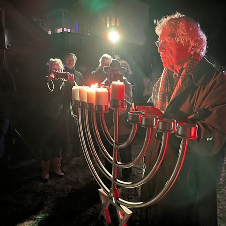 Ein Mann steckt Kerzen an einem Leuchter an.