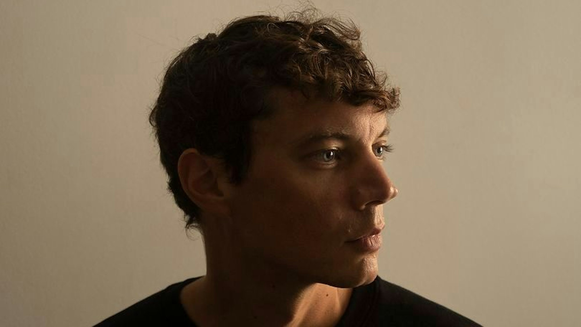 Francesco Tristano schaut seitlich zum Bild heraus.