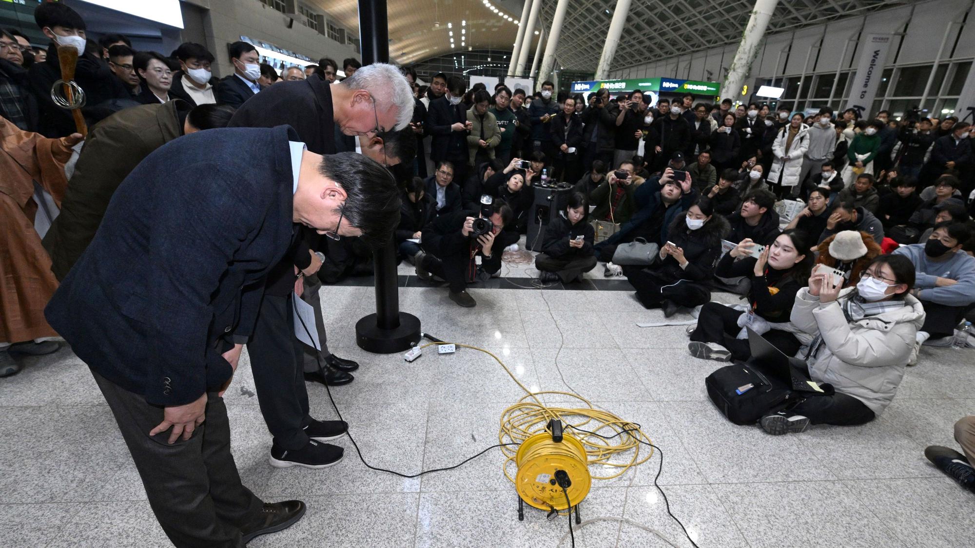 Der CEO von Jeju Air, Kim E-bae (l), und andere Mitglieder der Geschäftsführung verbeugen sich auf dem internationalen Flughafen Muan vor den Angehörigen der Passagiere. Bei der Landung am internationalen Flughafen von Muan in Südkorea ist ein Passagierflugzeug verunglückt.