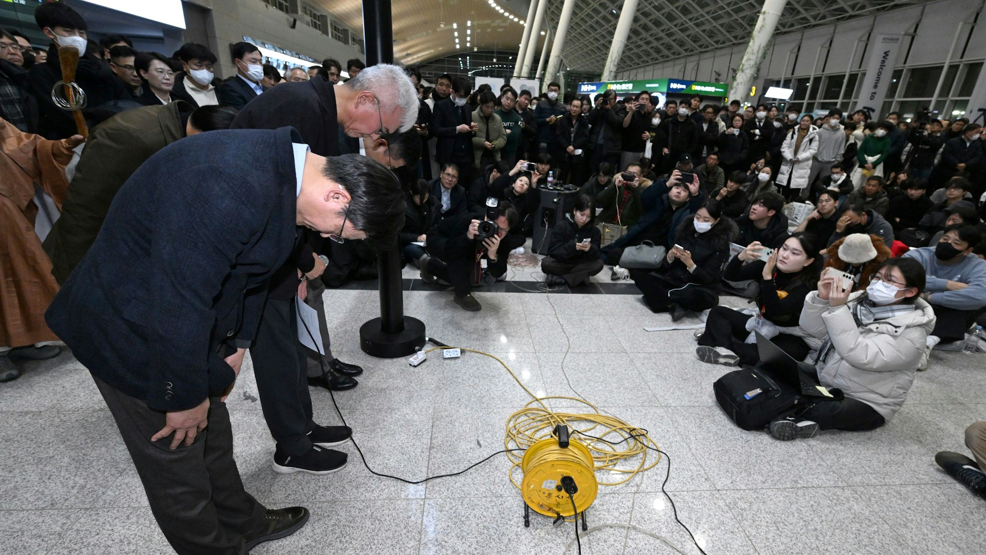 Der CEO von Jeju Air, Kim E-bae (l), und andere Mitglieder der Geschäftsführung verbeugen sich auf dem internationalen Flughafen Muan vor den Angehörigen der Passagiere. Bei der Landung am internationalen Flughafen von Muan in Südkorea ist ein Passagierflugzeug verunglückt.