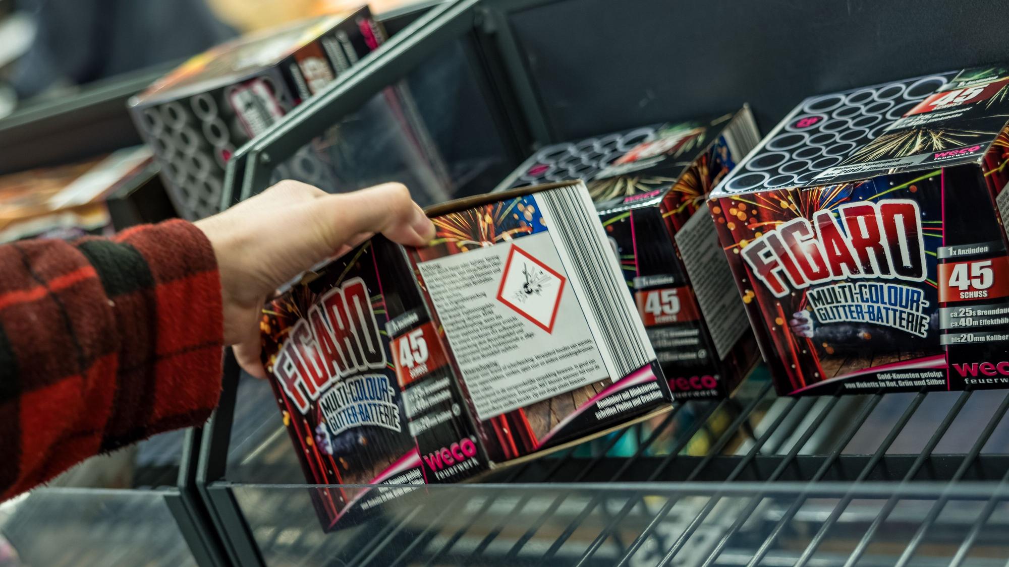 Ein Kunde eines Supermarktes nimmt Feuerwerk aus einem Regal.