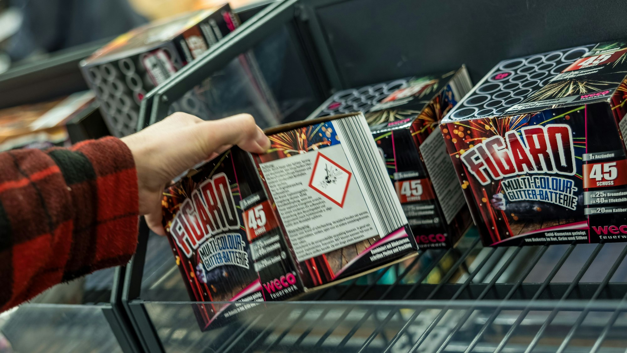 Ein Kunde eines Supermarktes nimmt Feuerwerk aus einem Regal.