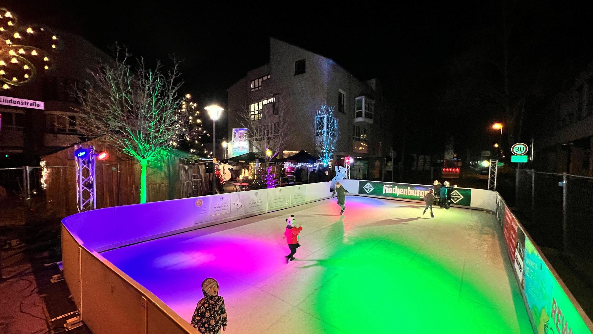 Eine bunt beleuchtete Eisbahn, auf der sich Kinder tummeln.