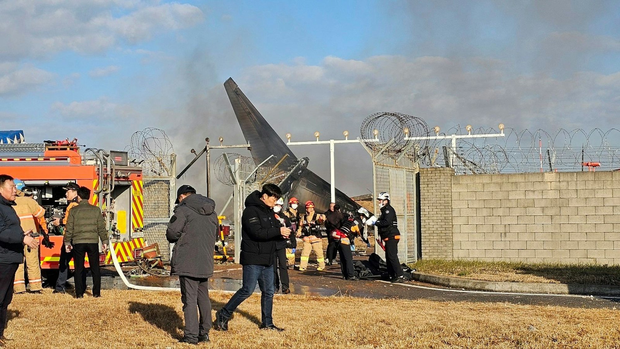 Zahlreiche Feuerwehrleute und Mitglieder des Rettungsteams arbeiten auf dem internationalen Flughafen von Muan, nachdem dort ein Passagierflugzeug verunfallt ist.