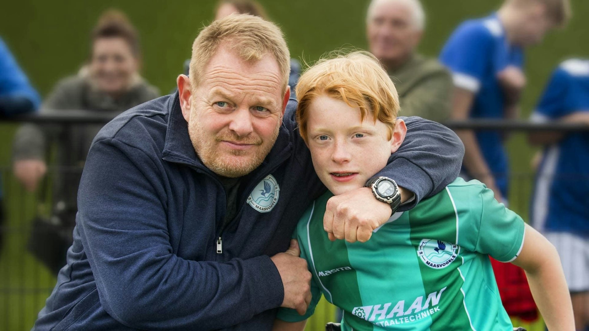 Ein Vater legt den Arm um den Hals seines Sohns.