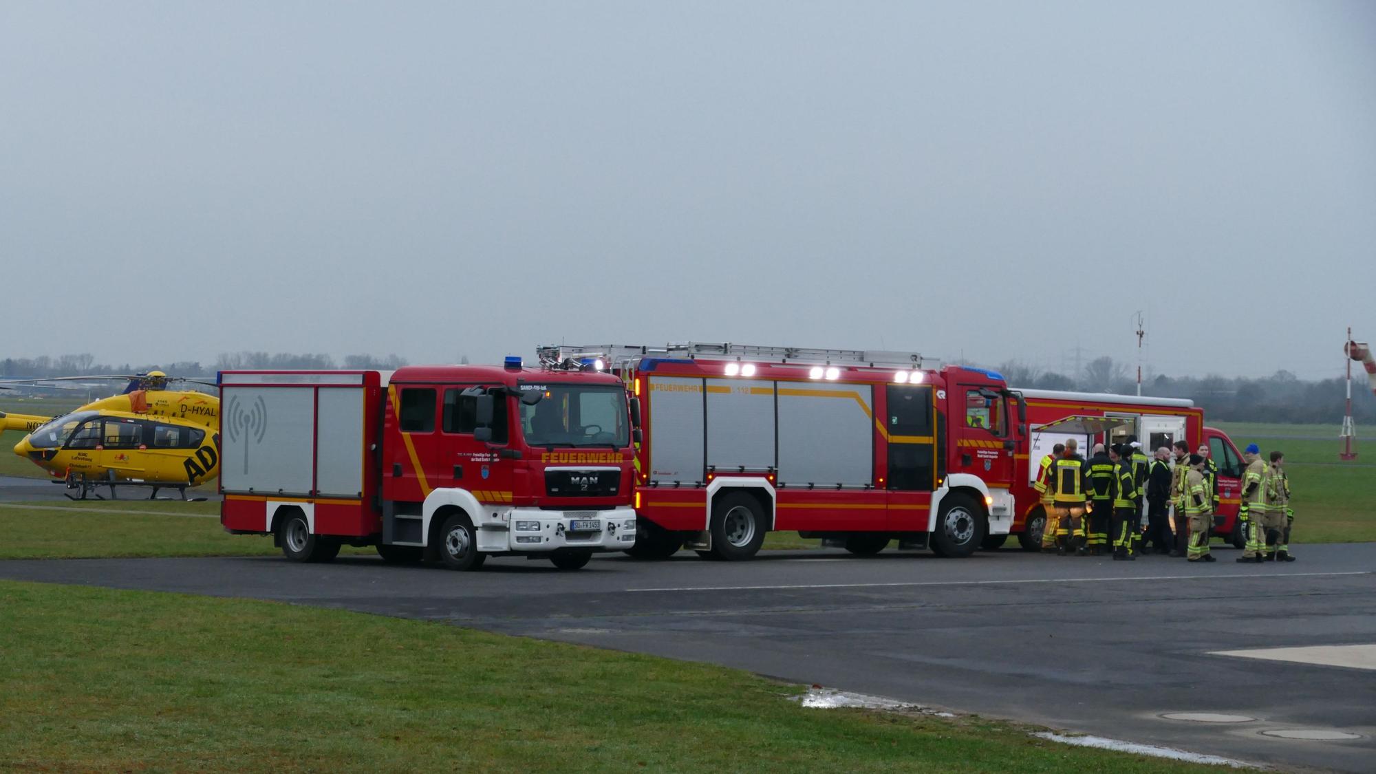 Feuerwehrleute stehen auf einem Flugplatz.