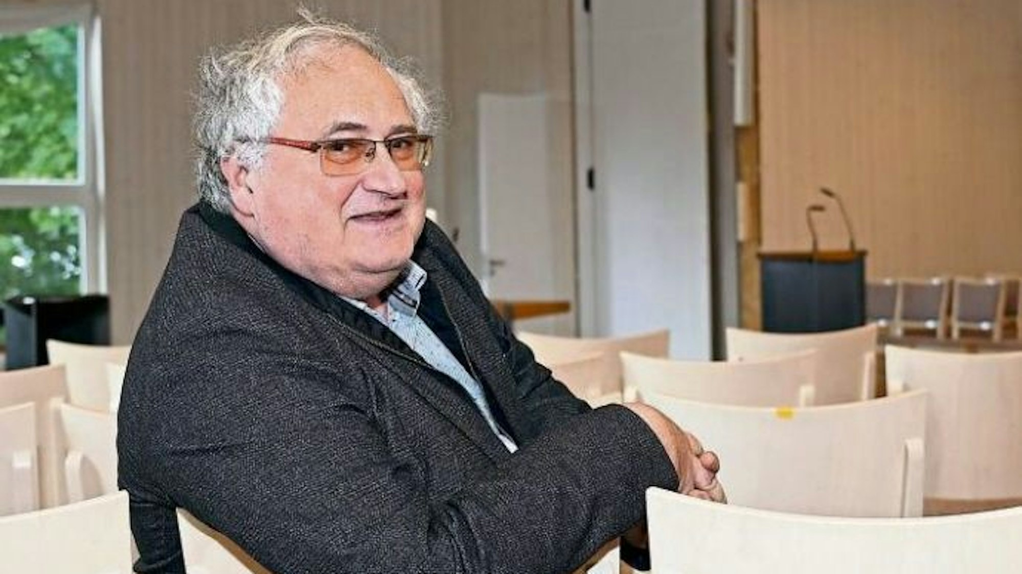 Pfarrer Karl-Ulrich Büscher sitzt im Gemeindesaal.