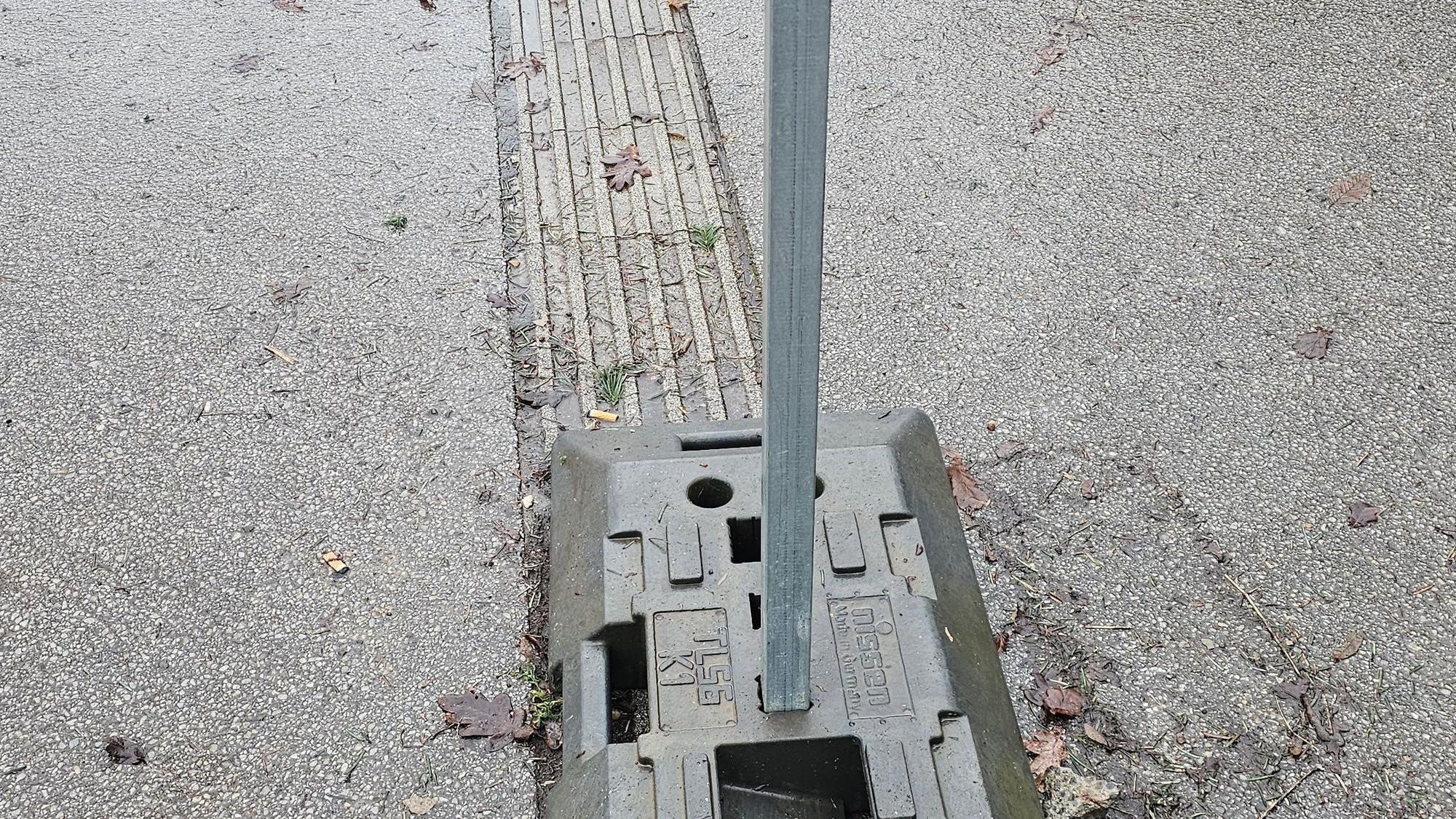 Auf dem Markierungsstreifen für Blinde steht der Fuß des Verkehrsschildes.