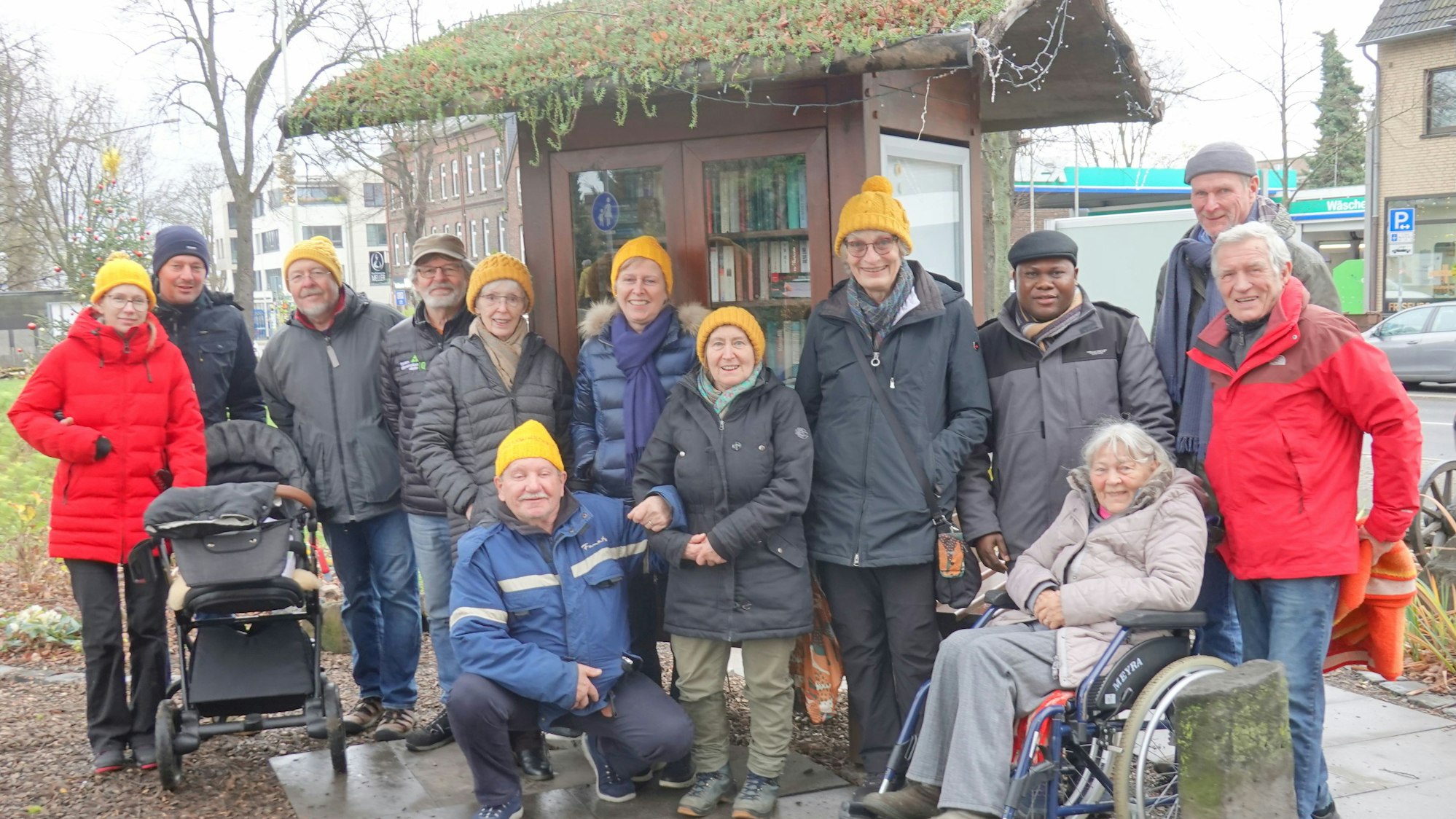 Auf dem Bild ist eine Gruppe Ehrenamtlicher vor dem Bücherschrank zu sehen.