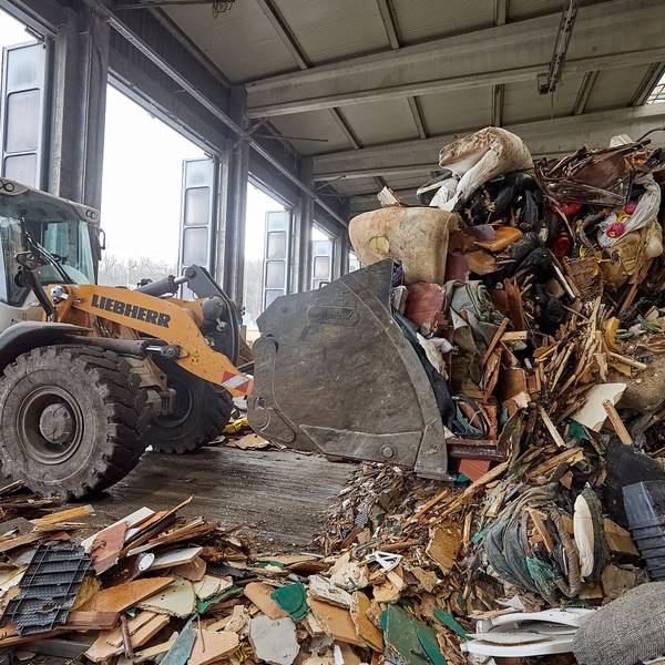 Das Bild zeigt einen Bagger, der im Abfallwirtschaftszentrum des Kreises Sperrmüll aufschüttet.