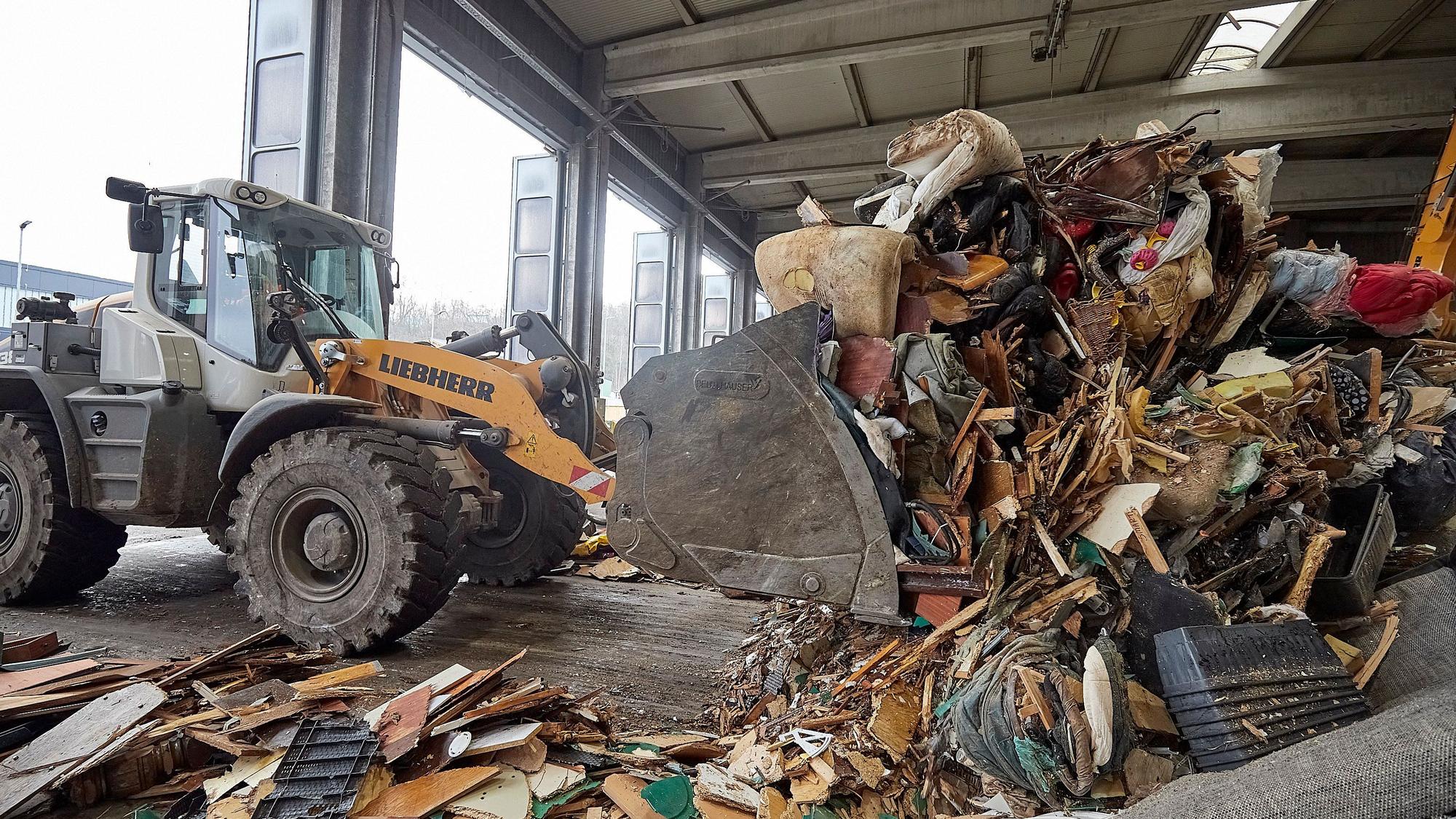 Das Bild zeigt einen Bagger, der im Abfallwirtschaftszentrum des Kreises Sperrmüll aufschüttet.