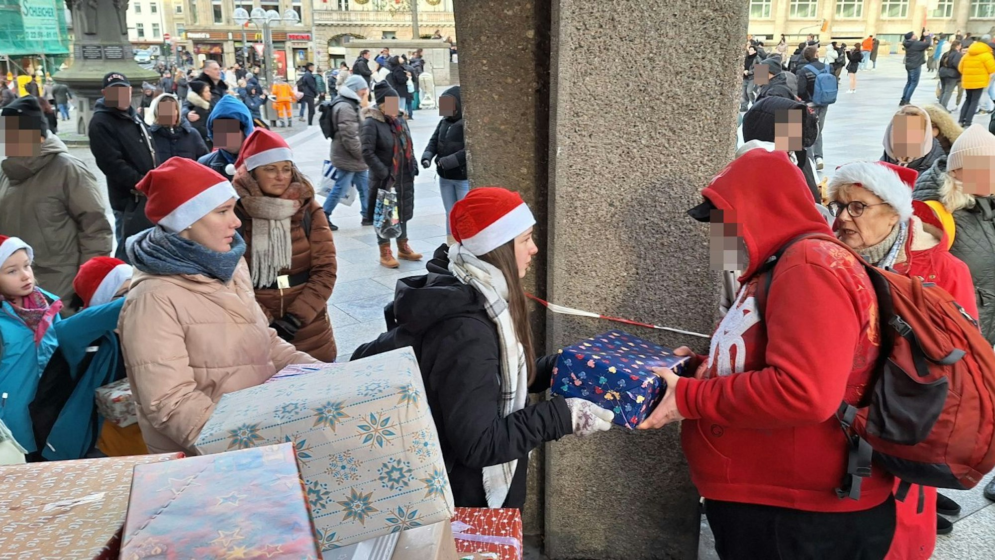 Kinder, die Weihnachtsmützen tragen, übergeben Bedürftigen Geschenke.