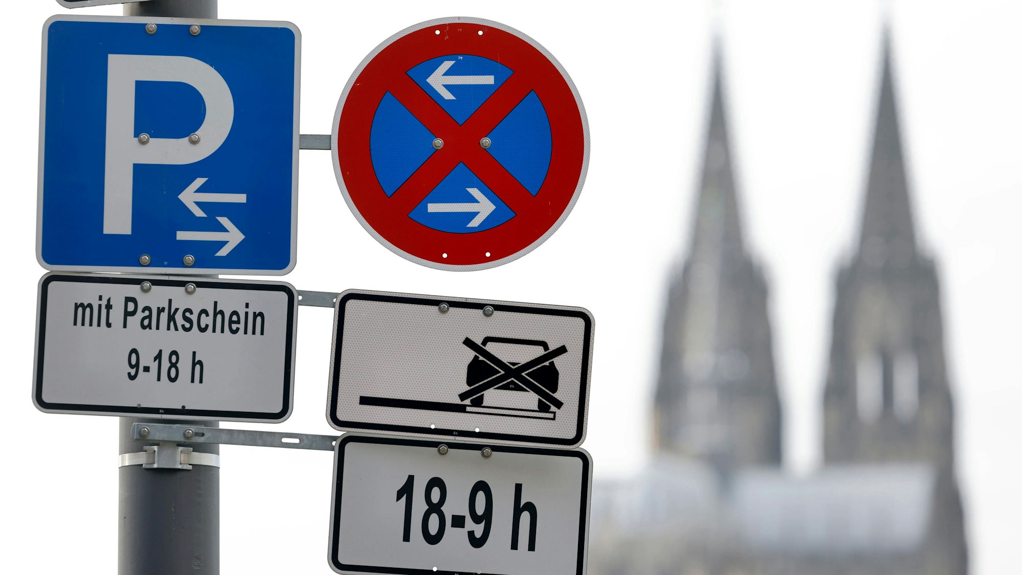 Im Bild ein Parkverbotsschild mit Parkplatzschild am Deutzer Rheinufer, im Hintergrund der Kölner Dom.