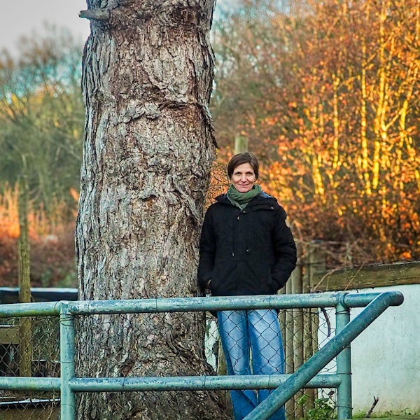 Christine Wynen lehnt sich an einen alten Baum auf dem Hof in Katzvey.