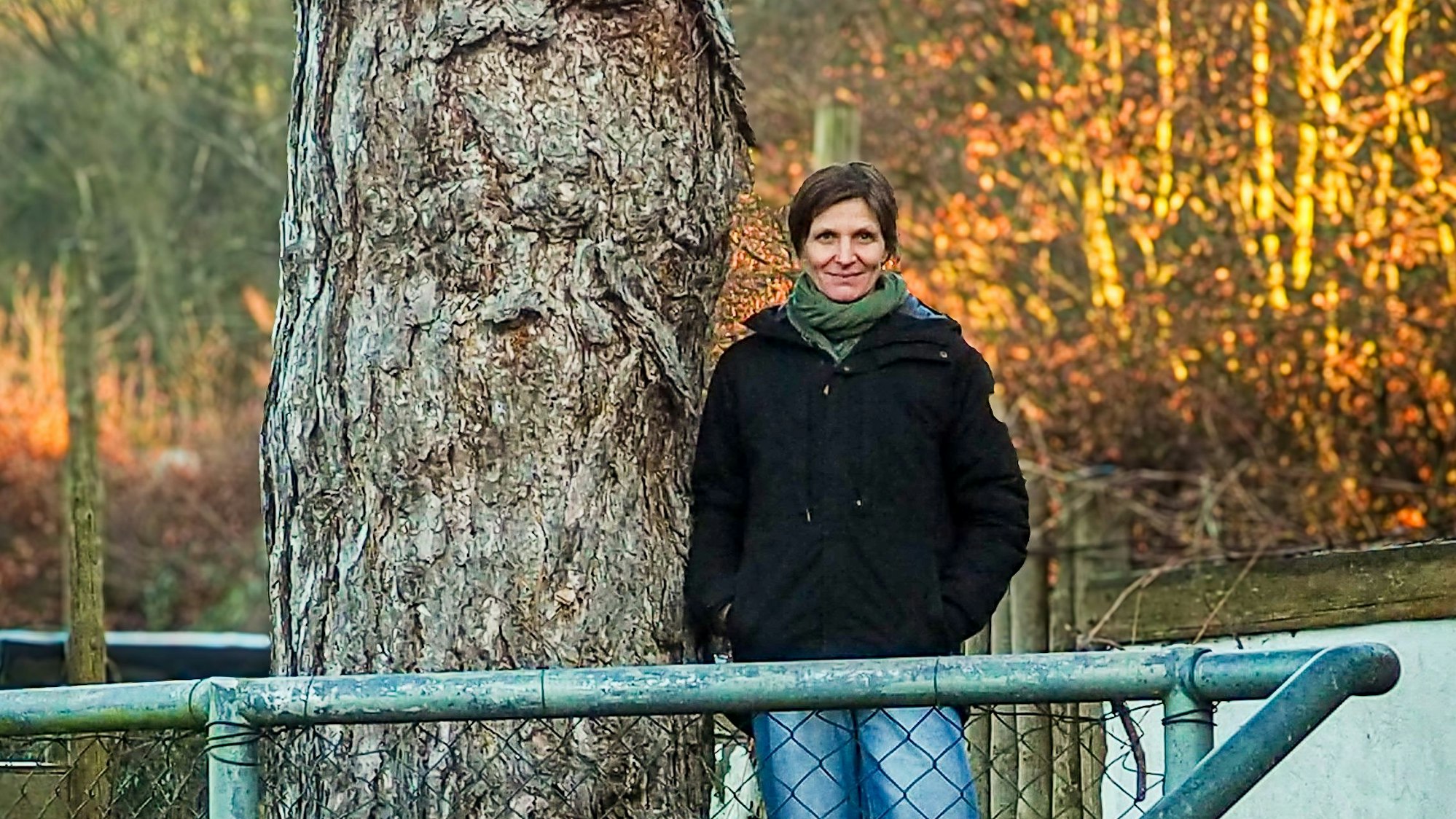 Christine Wynen lehnt sich an einen alten Baum auf dem Hof in Katzvey.
