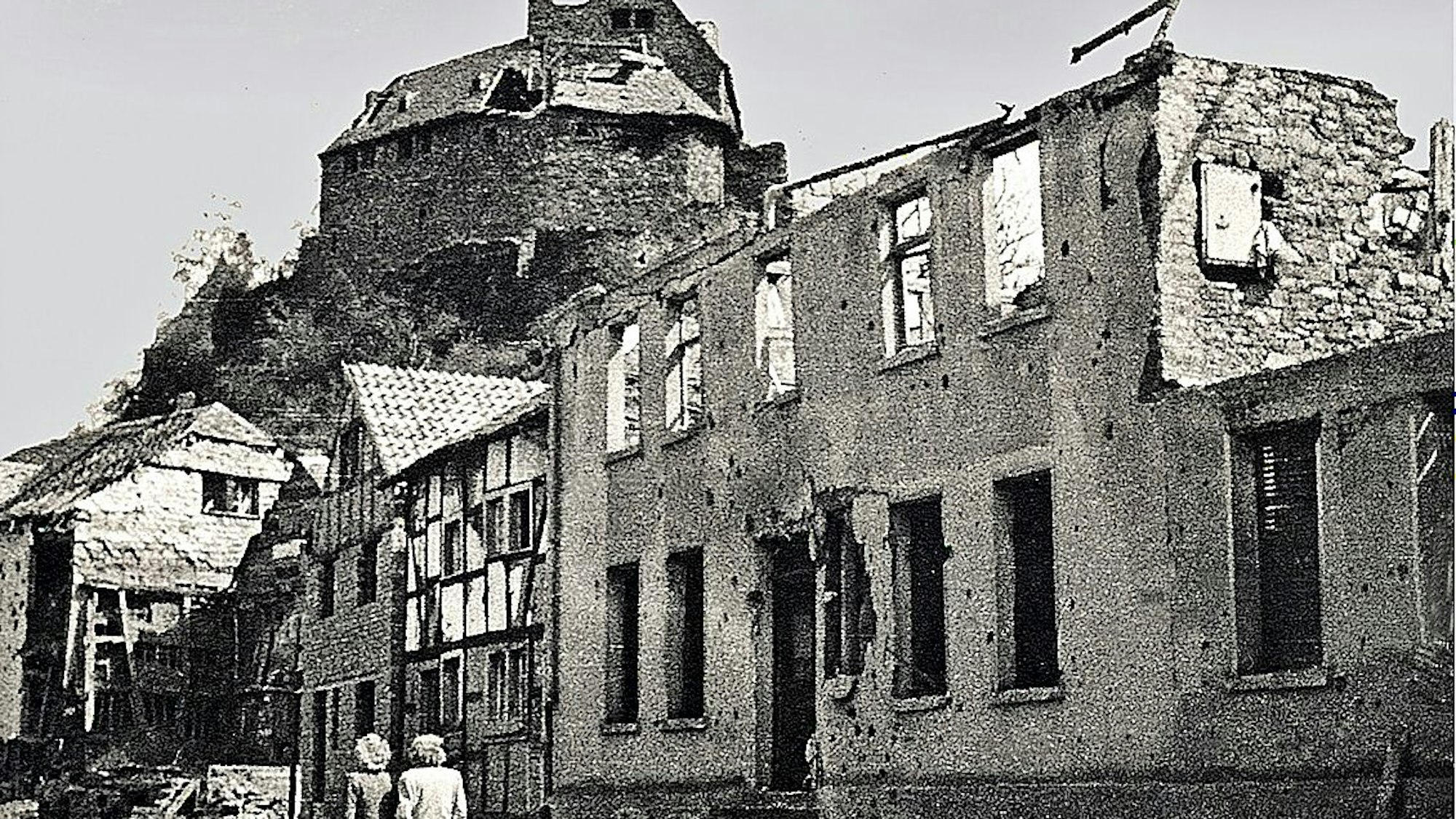 Das Repro eines historischen Fotos von 1946 zeigt das vom Krieg zerstörte Rathaus in Heimbach, dahinter die Burg.