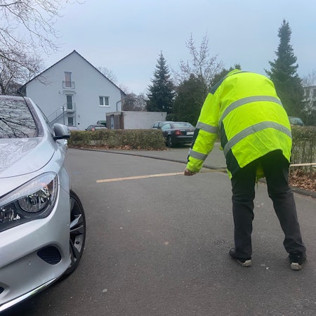 Ein Mann in einer gelben Warnweste prüft mit dem Zollstock, ob die Durchfahrtsbreite für Müllwagen reicht.
