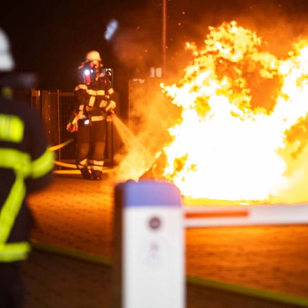 Die Feuerwehr gibt mit einem Feuerwehrschlauch Wasser auf ein Feuer ab.