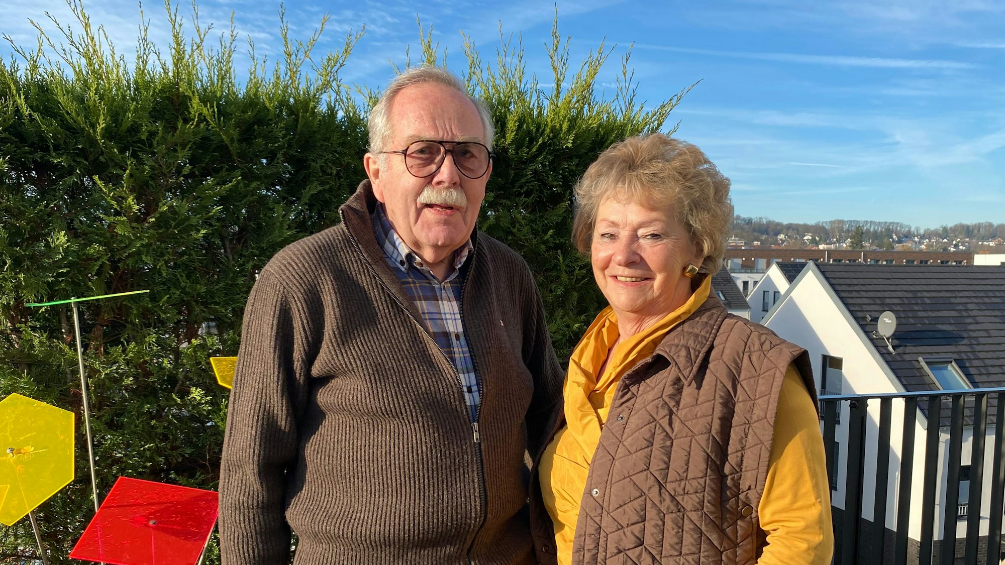 Auf dem Bild sind eine Frau und ein Mann, die sich um die digitale Teilhabe von Senioren kümmern, auf einem Balkon zu sehen.