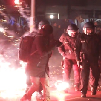 Einsatzkräfte der Polizei stehen in der Silvesternacht zwischen brennendem Feuerwerk.
