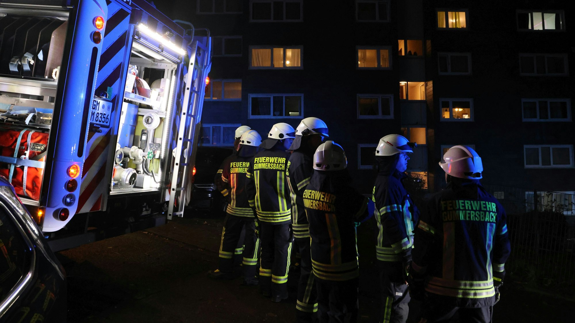 Feuerwehrleute stehen vor einem Haus.