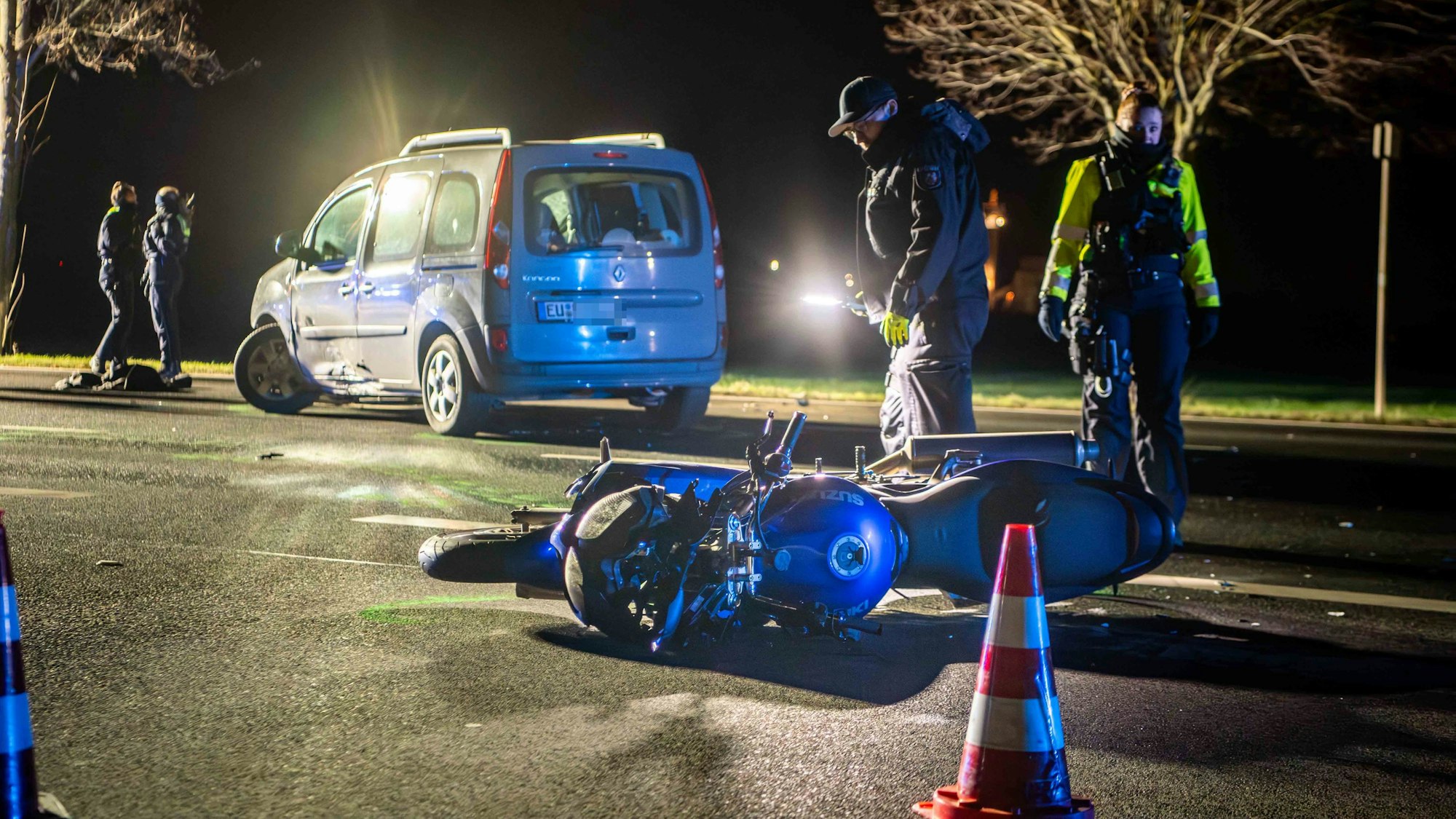 Nach einem Verkehrsunfall bei Euskirchen liegt ein Motorrad auf der Straße. Polizisten sichern Spuren. Im Hintergrund steht ein Auto.