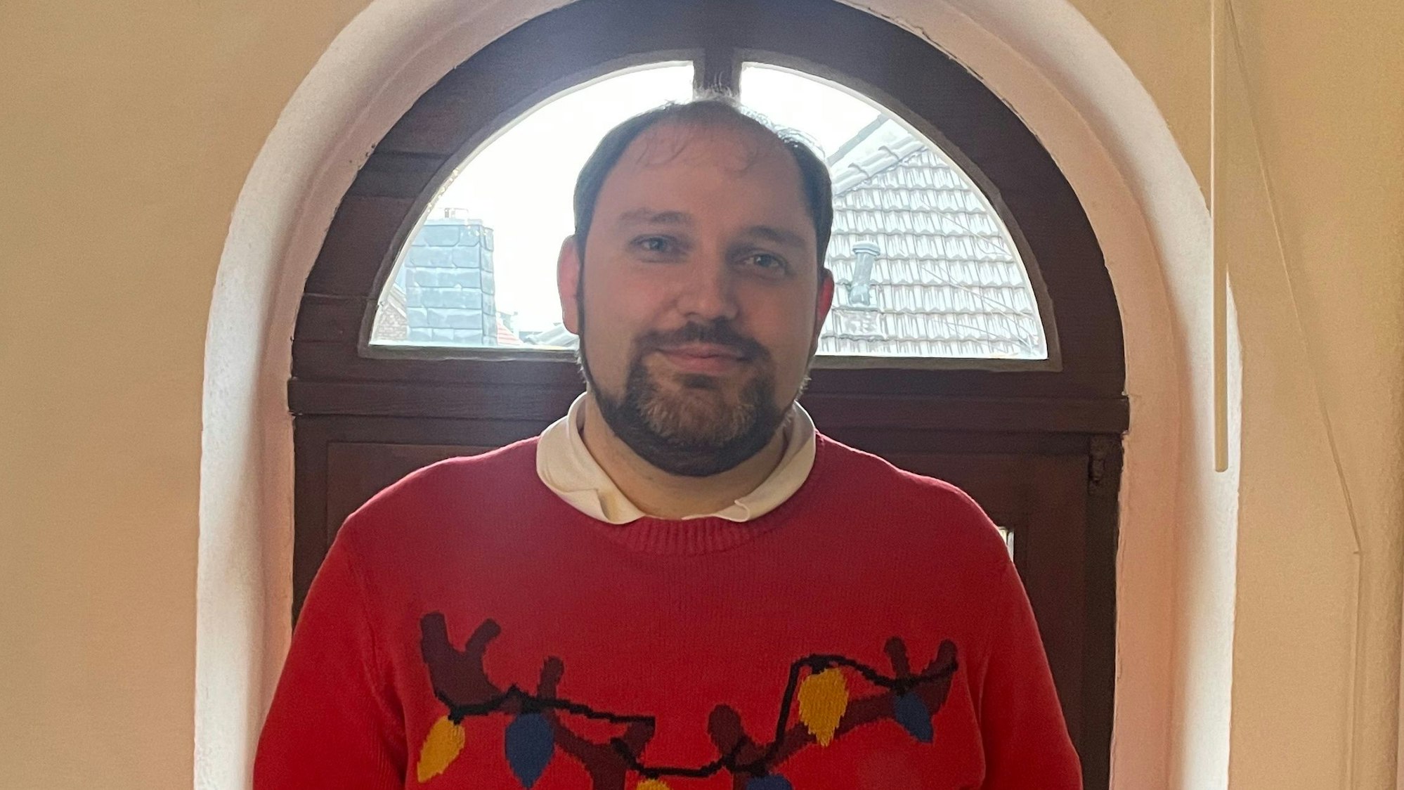 Auf dem Bild ist ein Mann im Weihnachtspullover zu sehen.