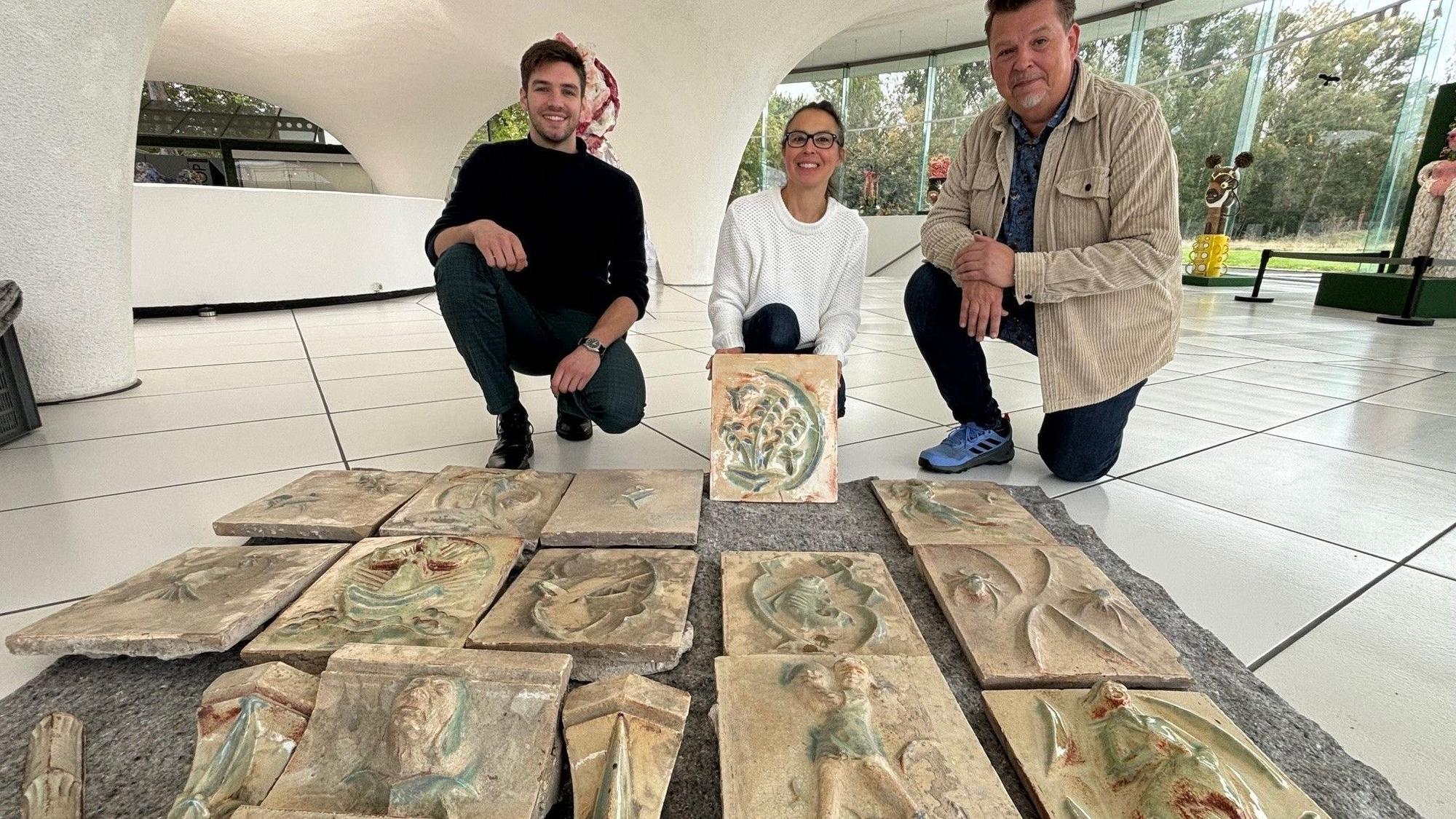 Auf dem Bild sind zwei Männer und eine Frau mit den alten Fliesen im Museum Keramion zu sehen.