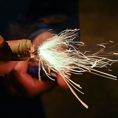 Ein Mann zündet einen Böller am Silvesterabend an.